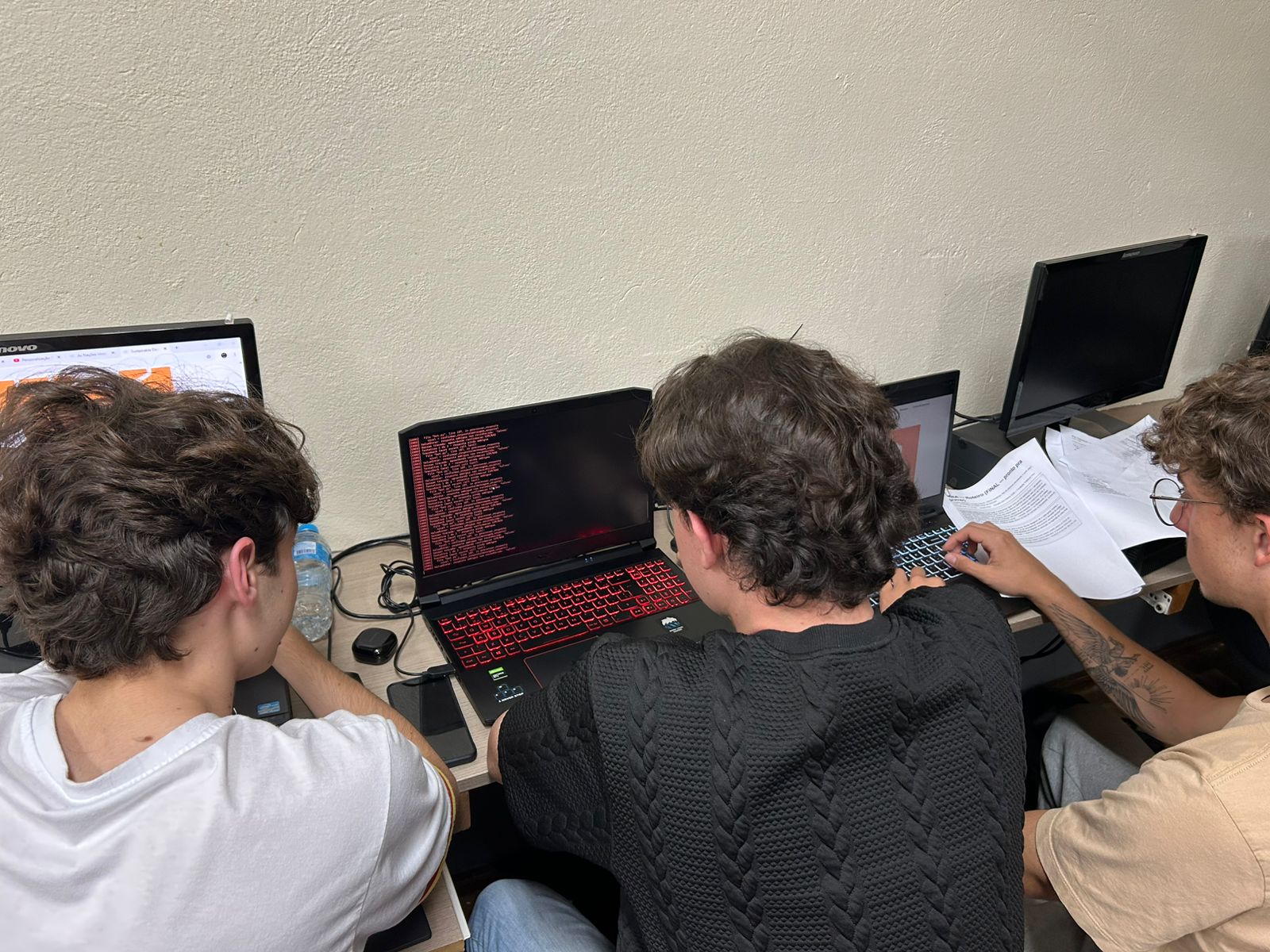 Tela de terminal cheia de erros em vermelho, com a equipe trabalhando ao fundo